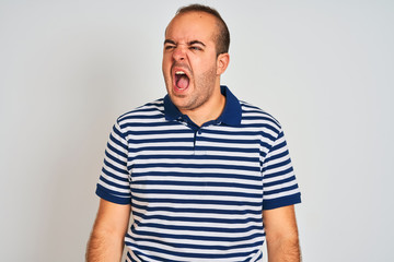 Sticker - Young man wearing casual striped polo standing over isolated white background angry and mad screaming frustrated and furious, shouting with anger. Rage and aggressive concept.