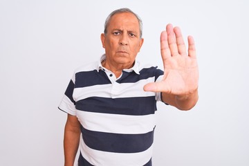 Wall Mural - Senior grey-haired man wearing casual striped polo standing over isolated white background doing stop sing with palm of the hand. Warning expression with negative and serious gesture on the face.