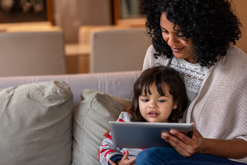 Wall Mural - Smiling mother and little daughter using a digital tablet together