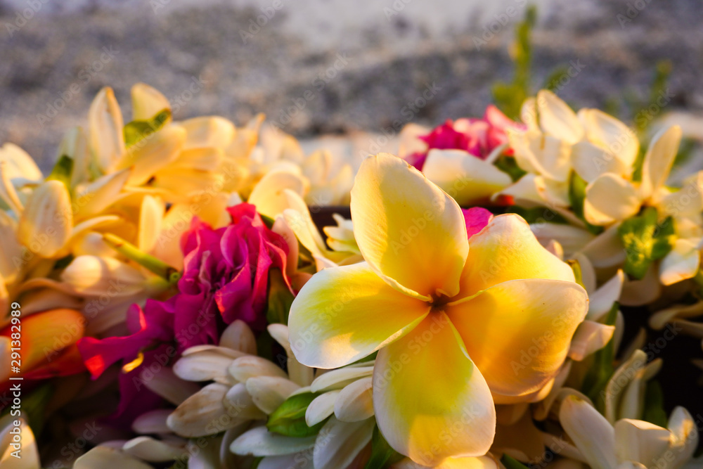 Close-up of a lei of tropical exotic flowers above a sandy beach  in French Polynesia in the South Pacific - obrazy, fototapety, plakaty 