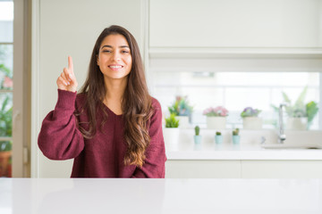 Sticker - Young beautiful woman at home showing and pointing up with finger number one while smiling confident and happy.