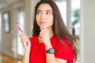 Wall Mural - Young woman holding dental toothbrush serious face thinking about question, very confused idea