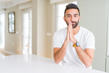 Canvas Print - Handsome hispanic man casual white t-shirt at home praying with hands together asking for forgiveness smiling confident.