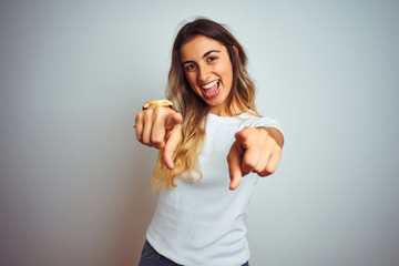 Wall Mural - Young beautiful woman wearing casual white t-shirt over isolated background pointing to you and the camera with fingers, smiling positive and cheerful