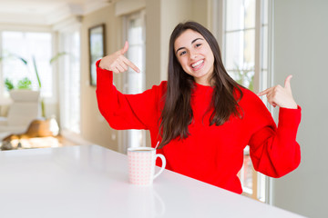 Sticker - Beautiful young woman drinking a cup of black coffee looking confident with smile on face, pointing oneself with fingers proud and happy.