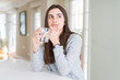© Krakenimages.com - Beautiful young woman drinking a fresh glass of water serious face thinking about question, very confused idea
