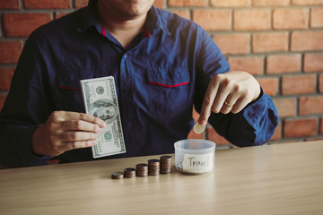 Wall Mural - Men are holding coins dropping to the money box with the concept of saving.