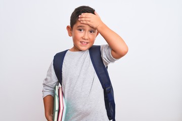 Poster - Beautiful student kid boy wearing backpack holding books over isolated white background stressed with hand on head, shocked with shame and surprise face, angry and frustrated