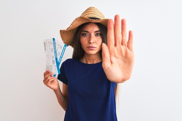 Wall Mural - Young beautiful tourist woman holding boarding pass ticket over isolated white background with open hand doing stop sign with serious and confident expression, defense gesture