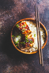 Wall Mural - Teriyaki chicken with rice in a wooden bowl, dark background.