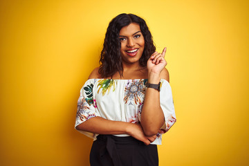Wall Mural - Transsexual transgender woman wearing summer t-shirt over isolated yellow background with a big smile on face, pointing with hand and finger to the side looking at the camera.