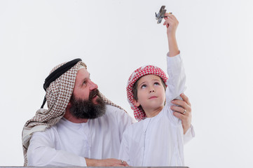 Arabic grandather and grandson playing together indoors using toy aircraft.