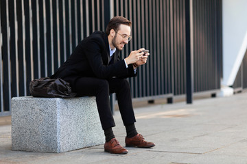 Wall Mural - Modern young man playing on phone, browsing mobile news. Gadget Dependence.