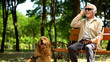 © motortion - Visually impaired man in earphones listening music in park, guide dog resting by