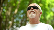 © motortion - Smiling man in black sunglasses enjoying beautiful nature in park, resting