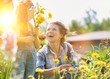 Mother and daughter picking pretty colourful flowers in their organic garden with yellow lens flare in background