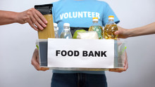 Volunteer Holding Food Bank Container, Hands Putting Provision In Box, Help