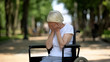 Depressed elderly female crying sitting in wheelchair at rehabilitation center