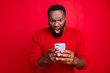 © deagreez - Close-up portrait of his he nice attractive irritated annoyed outraged bearded guy using wireless connection app 5g blog post smm spam messenger isolated over bright vivid shine red background