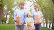 © motortion - Volunteers family holding paper bags with fruits outdoors, feeding homeless