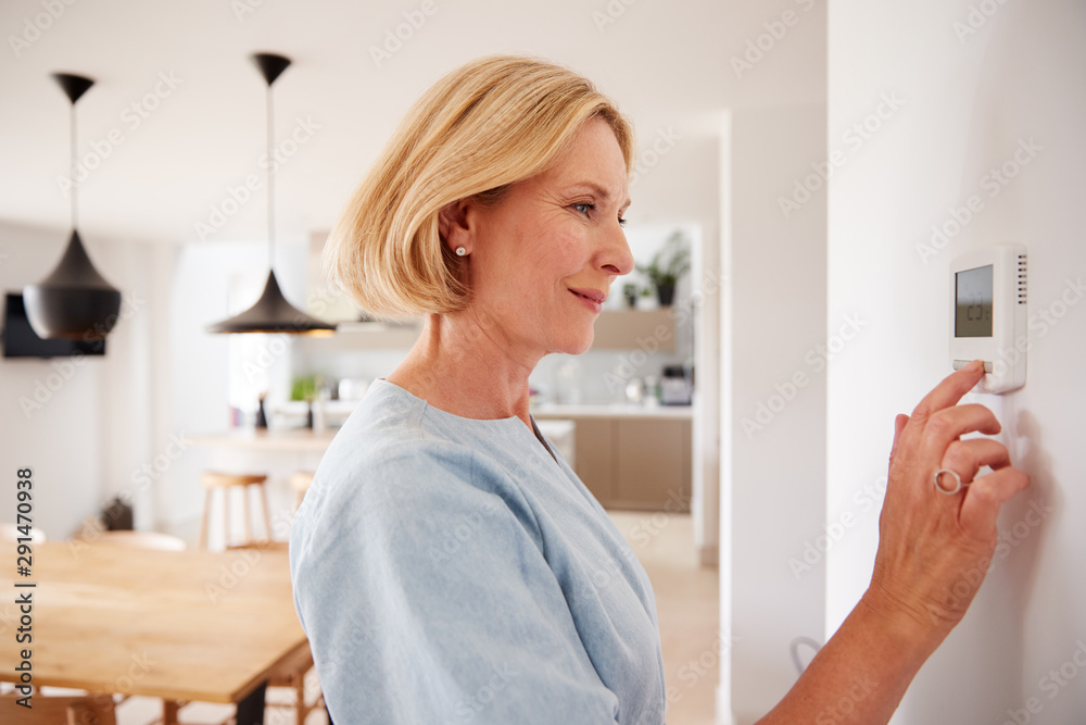 Close Up Of Mature Woman Adjusting Central Heating Temperature At Home On Thermostat - obrazy, fototapety, plakaty 