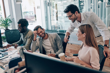 Canvas Print - Colleagues in smart casual wear communicating and using modern technologies while working in the office