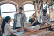 © gstockstudio - Group of young modern people in smart casual wear talking business ideas while working in the office