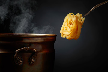 Homemade raw egg noodles and old brass pan with hot water.