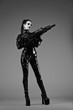 © Warpedgalerie - Portrait of a young woman in latex jumpsuit holding a machine gun in her hands