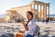 Attraktive Touristin mit Kamera in der Hand besucht die Akropolis von Athen während ihres Städtetrips, Griechenland