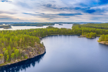 Poster - Aerial view of of small islands on a blue lake Saimaa. Landscape with drone. Blue lakes, islands and green forests from above on a cloudy summer morning. Lake landscape in Finland.