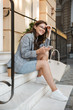 © Drobot Dean - Business lady outdoors at the street using mobile phone sit on steps.