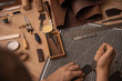 Working process in the leather workshop. Man's hands holding crafting tool