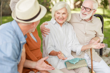 Joyful senior couple chatting with friends outdoors