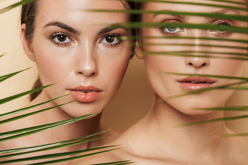 Serious women posing naked with green nature leaf plant.