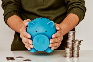 Man's hands holding piggy bank and coin stack. Concept of investment growth, business success and savings on white background with copy space