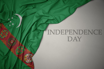 waving colorful national flag of turkmenistan on a gray background with text independence day.
