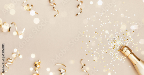 Fotomural Champagne bottle with confetti stars, bokeh decoration and party streamers on golden background