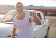 © Denis Rozhnovsky - A male driver stands near a white car with a key in his hand and smiles.