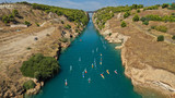 Fototapeta Na ścianę - Aerial bird's eye view photo taken by drone of stand up paddle surfers in annual SUP crossing competition in Corinth Canal, Greece
