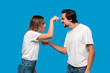 © ianachyrva - Couple of a young blond woman and brunet bearded man with mustaches in white t-shirts and blue jeans quarreling standing isolated over blue background.