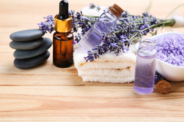 Wall Mural - Lavender flowers with oil in bottle, salt and spa stones on brown wooden table