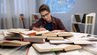 School books on table, male teenager in eyeglasses writing homework essay, hobby