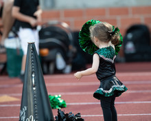 Cute Little Girl Dressed In A Cheerleader Costume At A Football Game
