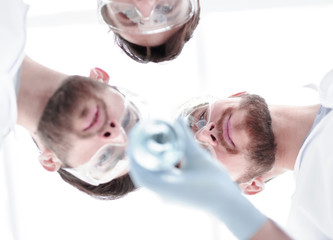 Wall Mural - closeup.a group of scientists looks at the liquid in the beaker