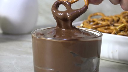 Wall Mural - Dipping a salted pretzel into melted milk chocolate, slow motion