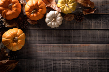 Wall Mural - top view of autumn maple leaves with pumpkin, apple, corn and red berries on old wooden background. 