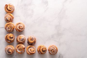 Homemade baked cinnamon rolls with marble slab background and space for text.