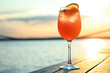 Glass of fresh summer cocktail on wooden table outdoors at sunset. Space for text