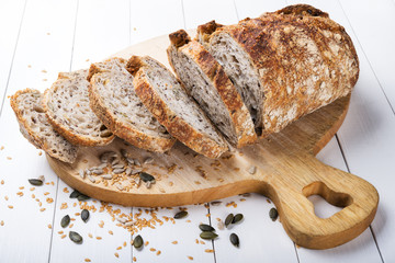 Organic seed bread. Sourdough bread. Bread cut in slices on a white wood background.